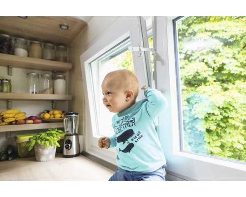 Siguranță pentru copii pe o fereastră basculantă cu un bebeluș în față.