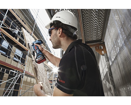 Meșterul taie o scândură de lemn cu un fierăstrău vertical cu acumulator pe un șantier