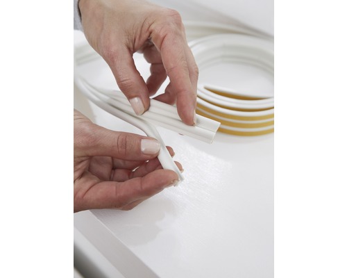 Mâini care țin o bordură decorativă albă cu bandă adezivă