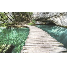 Pod de lemn peste lac turcoaz către o peșteră