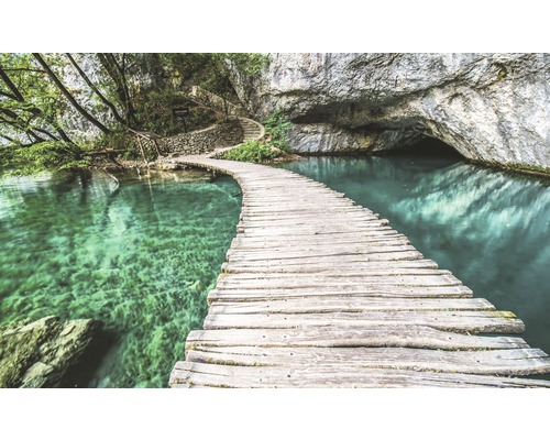 Pod de lemn peste lac turcoaz către o peșteră