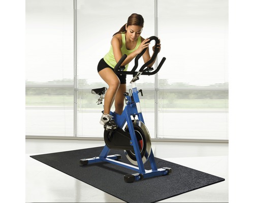 Femeie care se antrenează pe o bicicletă de interior albastră pe o saltea neagră