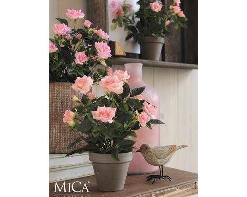 Trandafiri decorativi într-un ghiveci pe o masă cu un decor din lemn în formă de pasăre și o vază.