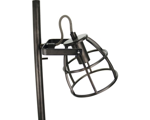 Prim-plan al unei lămpi de podea cu abajur metalic tip grilaj.