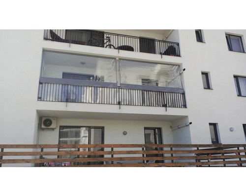 Balcon cu paravan de intimitate și balustradă pe o clădire rezidențială.