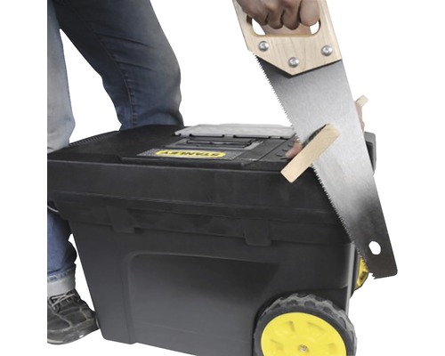 Persoană taie lemn pe o cutie de scule mobilă Stanley.