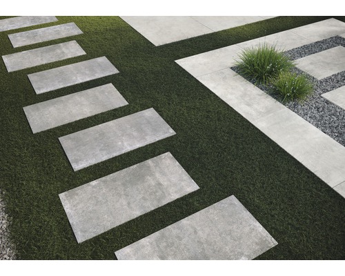Amenajare grădină cu plăci dreptunghiulare de piatră ca o potecă pe un gazon.