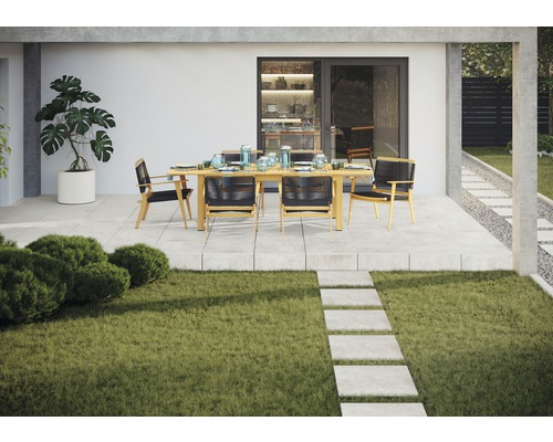 Scenă de grădină cu masă de sufragerie și scaune pe o terasă lângă un gazon