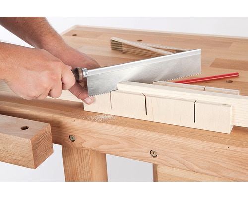 Artizan care taie lemn cu un ferăstrău și o cutie de mitră pe un banc de lucru