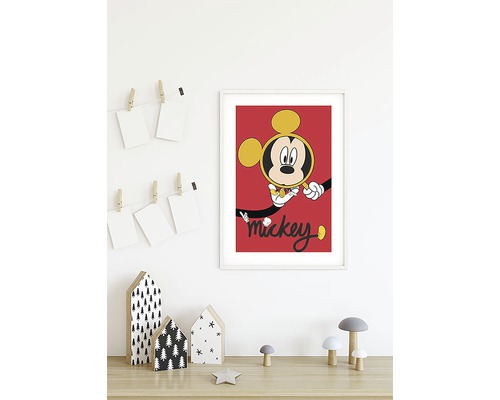 Poster înrămat cu Mickey Mouse pe un perete deasupra unei mese cu elemente decorative