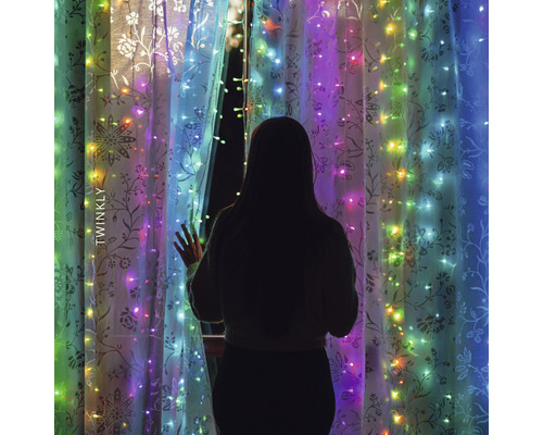 Femeie stând în fața ferestrei cu ghirlandă luminoasă Twinkly