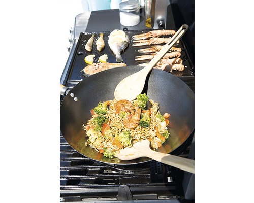 Wok cu legume și creveți, precum și pește și fructe de mare preparate pe un grătar.