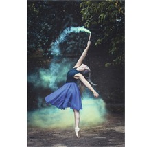 O balerină dansează cu o torță fumigenă într-o pădure.