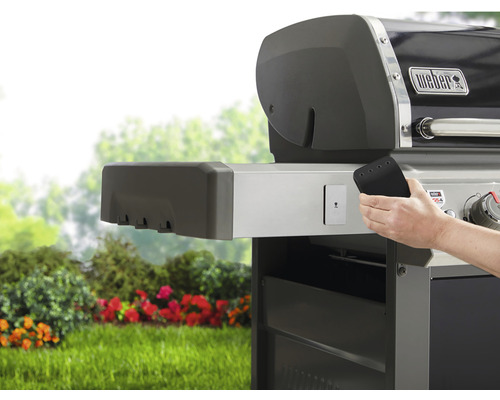 Grătar Weber cu o mână care ține o unealtă pentru grătar