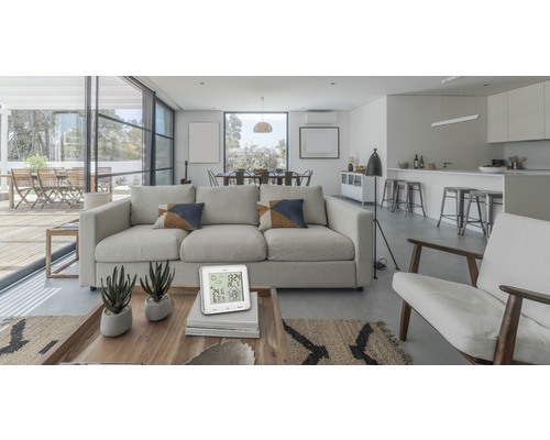 Living luminos cu canapea, fotolii, masă de sufragerie și termometru digital pe o măsuță de cafea