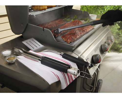 Scenă de grătar cu coaste, clește pentru grătar, spatulă, pensulă și condimente pe un grătar