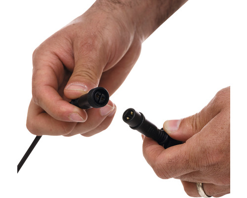 Două mâini țin un conector electric de cablu
