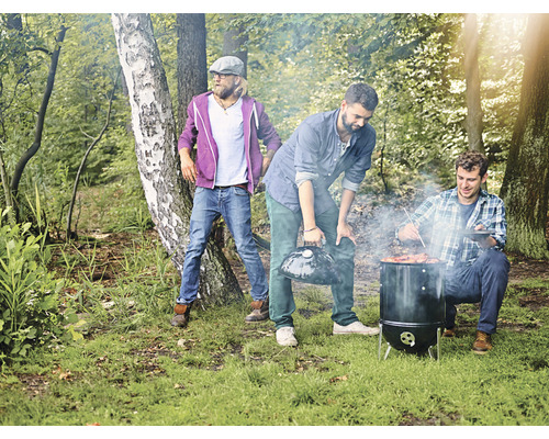 Scenă de grătar în aer liber cu trei bărbați care fac grătar în pădure.