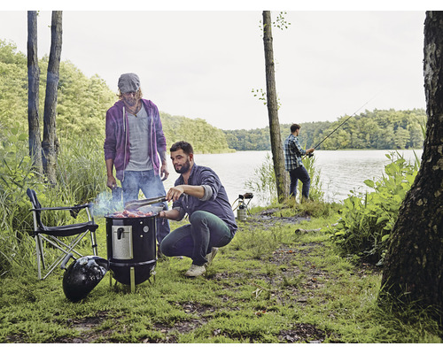 Scenă cu bărbați făcând grătar la lac, un grătar cu cărbune și un pescar