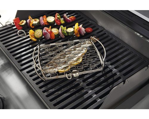 Pește în coș de grătar pentru pește și frigărui de legume pe un grătar