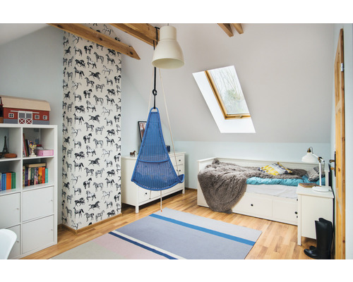 Cameră luminoasă pentru copii cu coș suspendat, pat și bibliotecă sub o fereastră de mansardă.