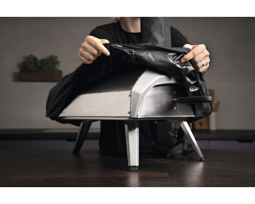 Persoană care pune o husă pe un cuptor de pizza.