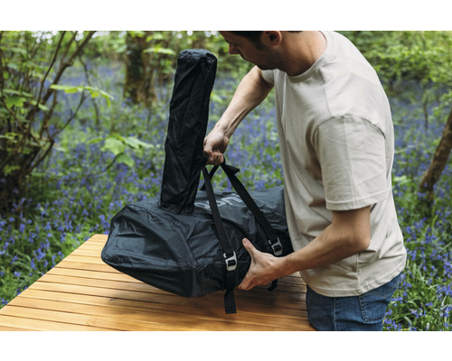 Bărbat împachetând un pat de camping ambalat pe o masă