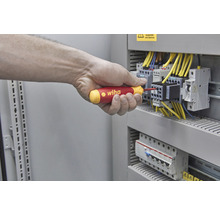 O mână înșurubează cu o șurubelniță Wiha la o cutie de siguranțe.