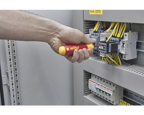 O mână înșurubează cu o șurubelniță Wiha la o cutie de siguranțe.