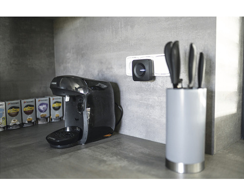 Cafetieră lângă priză cu receptor wireless și bloc de cuțite pe un blat de bucătărie