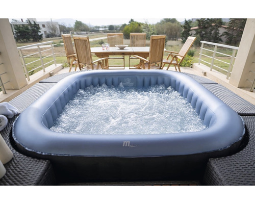 Cada cu hidromasaj gonflabilă cu apă spumantă pe o terasă cu mobilier de grădină