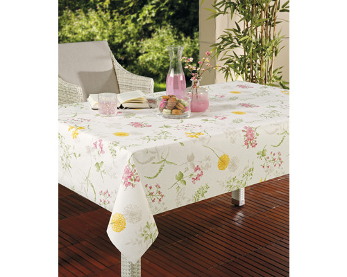 Scenă de grădină cu o masă acoperită cu o față de masă florală, băuturi și mâncare.