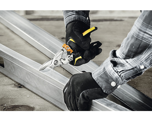 O persoană taie un profil metalic cu o foarfecă de tablă.