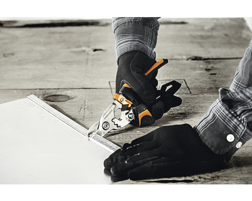 O persoană taie o foaie de metal cu foarfece de tablă.