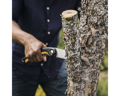 Persoană taie o ramură cu un ferăstrău de mână