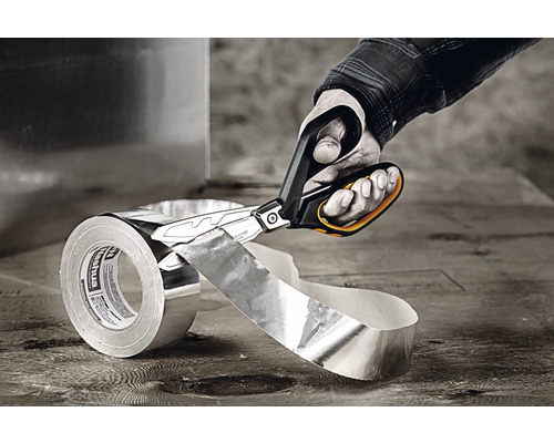 O mână taie o bucată de bandă adezivă din aluminiu cu foarfece de tablă.