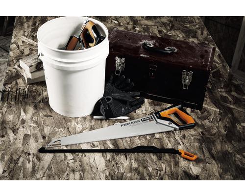 Scenă cu un fierăstrău manual, o cutie de scule, o găleată și mănuși de lucru pe o suprafață de lucru