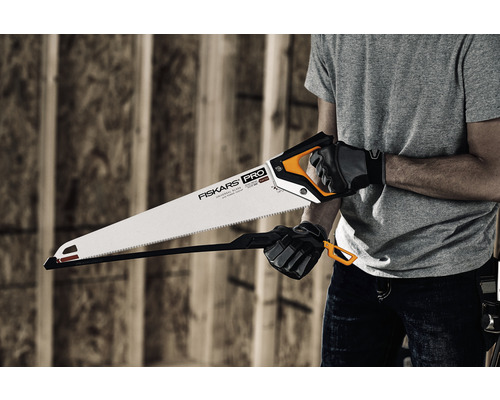 O persoană ține un ferăstrău manual Fiskars Pro cu protecție pentru lamă.