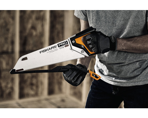 Un bărbat ține un fierăstrău manual marca Fiskars