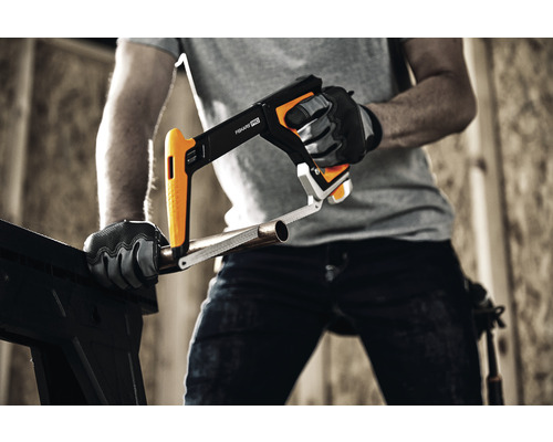 Artizan care taie o țeavă cu un fierăstrău pentru metal Fiskars.