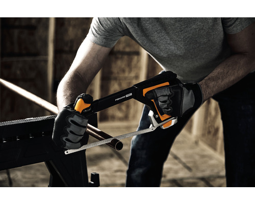 Un bărbat taie o țeavă cu un fierăstrău.