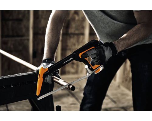 Persoană taie țeavă de cupru cu un ferăstrău pentru metal Fiskars