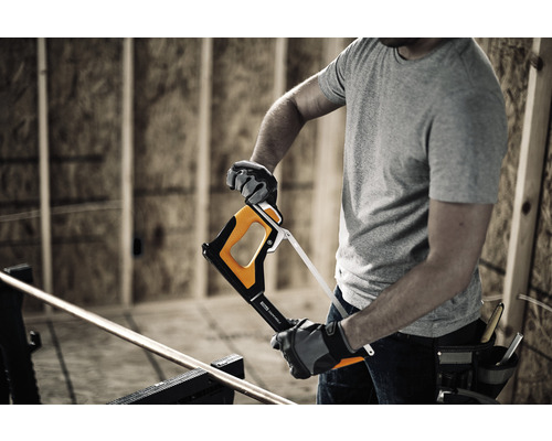 Un bărbat taie o țeavă metalică cu un fierăstrău.