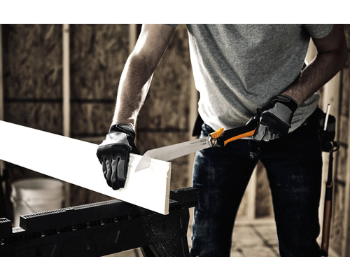 Un bărbat taie o scândură de lemn cu un ferăstrău manual pe un cal de lucru.