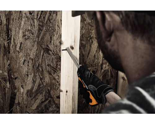 O persoană taie o scândură de lemn cu un ferăstrău manual.