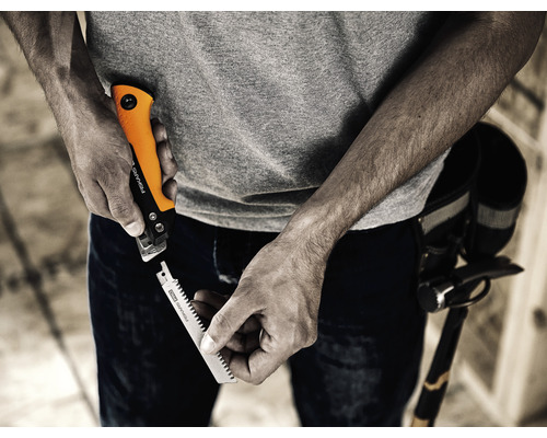 Un bărbat schimbă lama de ferăstrău la suportul de lamă de ferăstrău Fiskars