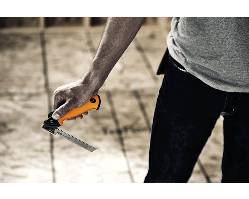 O persoană ține un ferăstrău vertical cu mâner portocaliu.