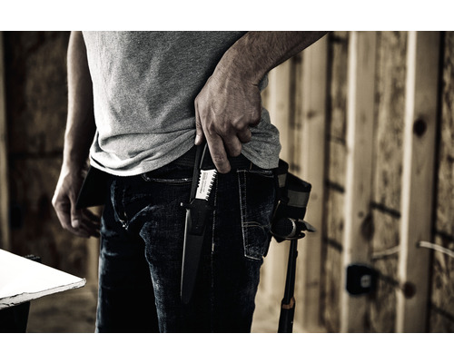 O persoană cu un ferăstrău manual într-un toc la curea într-un mediu de lucru.