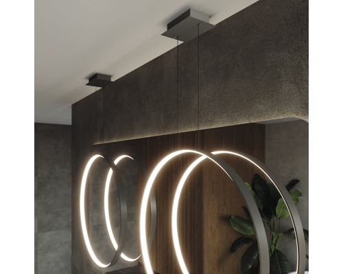 Trei corpuri de iluminat suspendate cu LED circulare într-o cameră mobilată modern