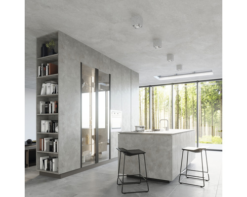 Bucătărie luminoasă cu insulă de gătit, scaune de bar, rafturi și ferestre mari cu vedere la pădure